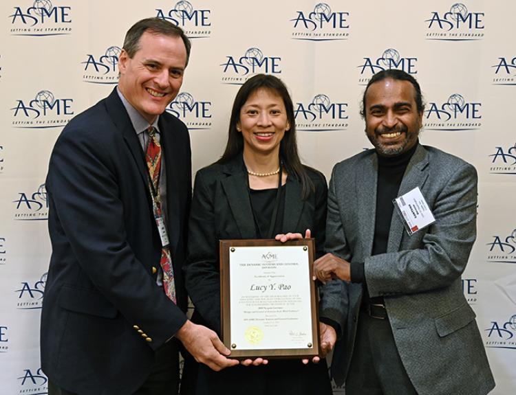 Lucy Pao accepting her award with two presenters