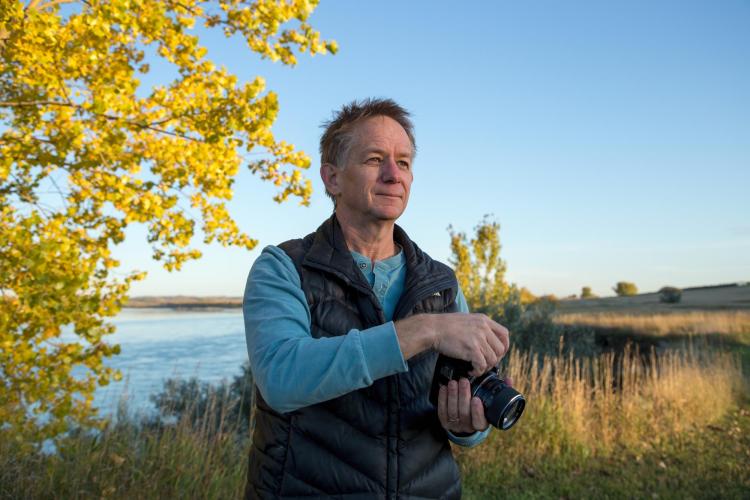 Kent with his camera by a lake with fall trees