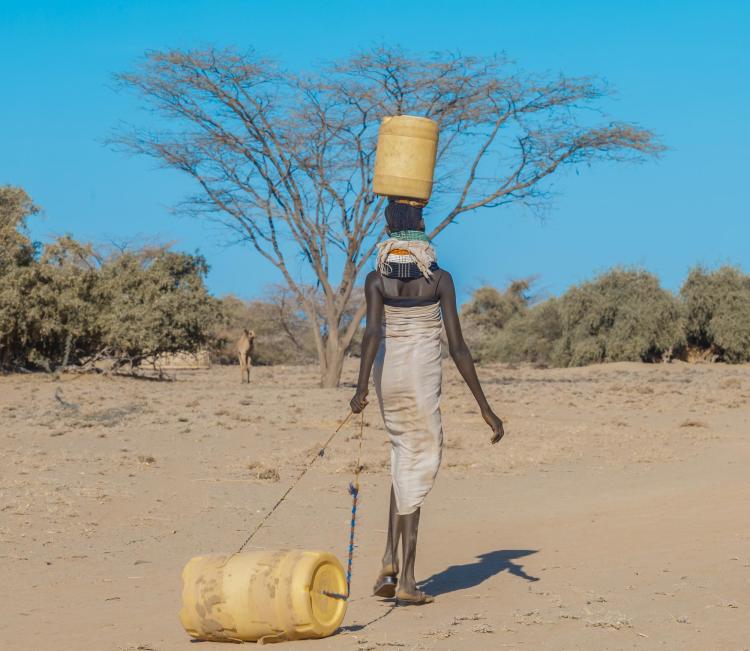 A woman dragging a water barrel in Africa