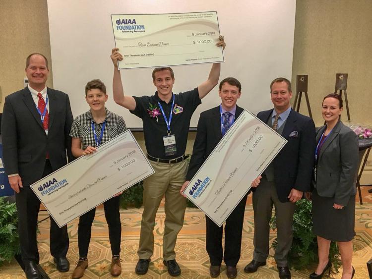 Students from the winning teams with oversized prize checks.