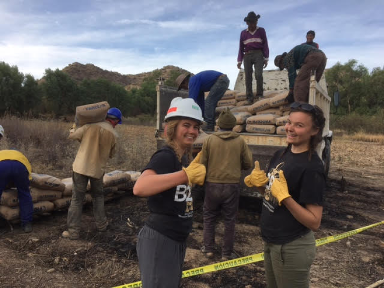 Two crew members flash a thumbs-up while helping to unload a truck at the Bolivia worksite.