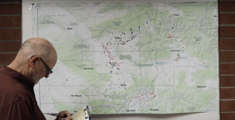 A worker makes notes on a physical map of sampling locations.