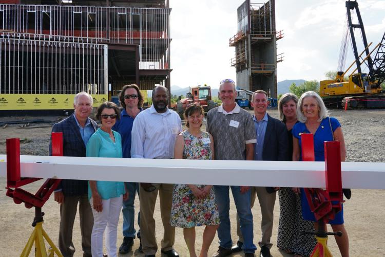 A group of officials standing with the final beam.