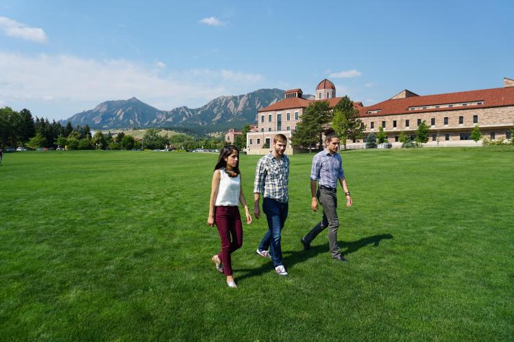 Graduate students walk across field on campus