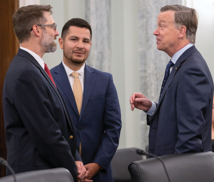 Marcus Holzinger, left, chats with Colorado Sen. John Hickenlooper, right, after his congressional appearance.