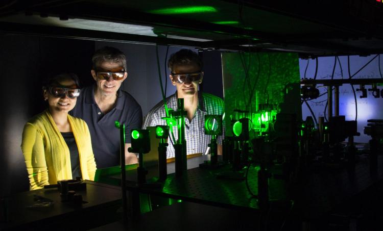 Rafael Piestun and his students standing in a lab with a laser