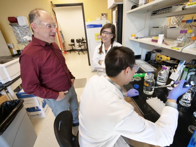 Karl Linden chats with two grad students in his lab.