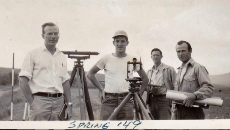Four students standing with surveying equipment