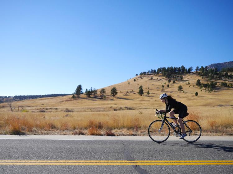A woman rides her bike along a Boulder backroad.