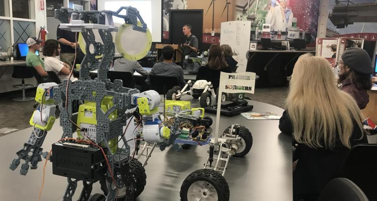 A robot sits in the foreground as Bobby talks to students at Pueblo Community College’s STEM Center.