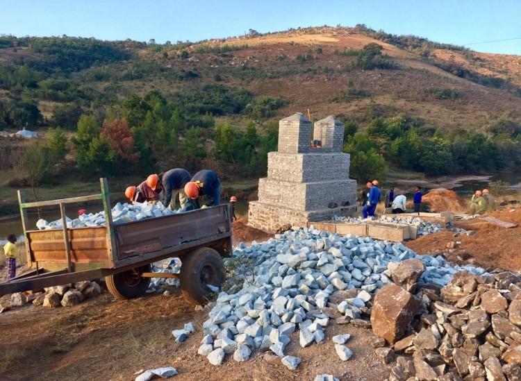 Crew members unload rocks from a trailer at the Swaziland bridge site.