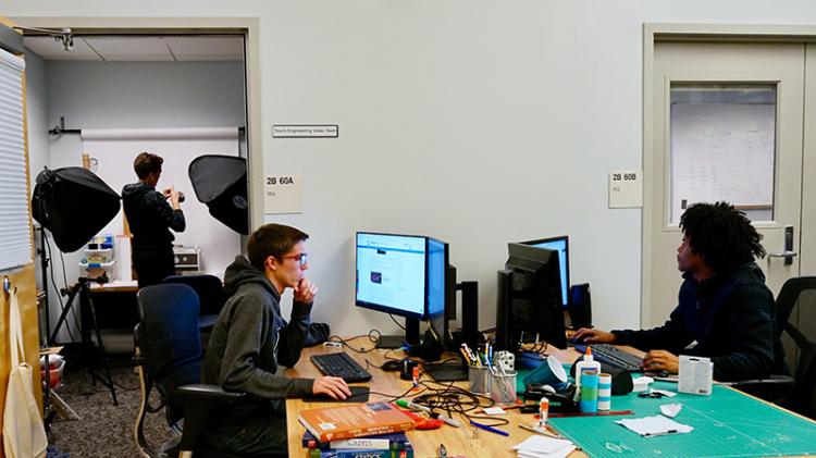 Three students working on creating content for the library