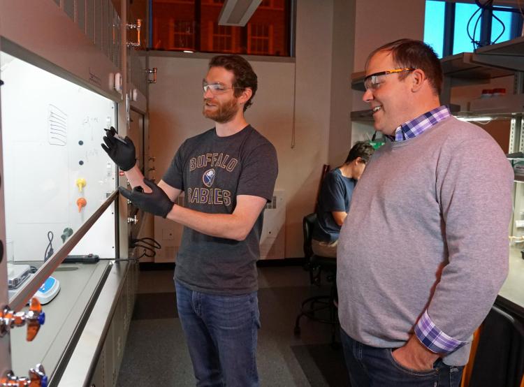 Tim White with a student in his lab looking at work on the wall