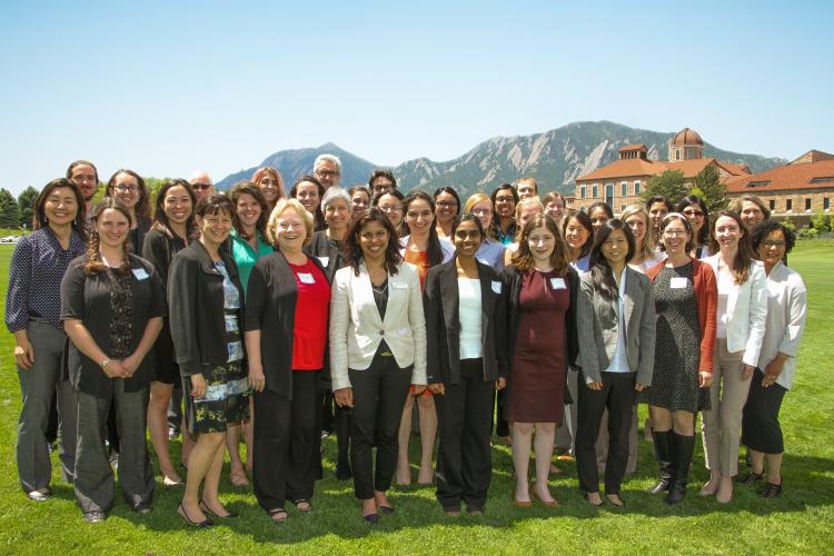 The Women in Aerospace Symposium standing for a group photo outside with the Flatirons in the background.