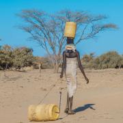 A woman dragging a water barrel in Africa 