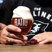 Hand holds a foamy glass of Ratio beer