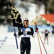 Magnus Boee on a ski slope holding a CU flag.