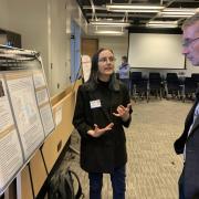 A research presents their poster to Acting Dean Keith Molenaar