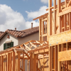 A fully built home with a tile roof next to a partially built, framed home.