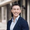 Wil Srubar in a suit coat and button down shirt in front of a blurred building