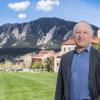 Professor Karl Linden stands on the CU Boulder campus with the Flatirons and campus buildings in the background on a sunny day.