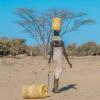 A woman dragging a water barrel in Africa 