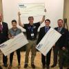 Students from the winning teams with oversized prize checks.