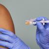 closeup of doctors hands holding a vaccine near someone's arm