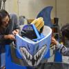 Two students add CU Boulder lettering to the concrete canoe