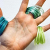 A hand holding three coils of multicolored biofiber thread