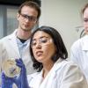A faculty member shows three students a biologic sample in their lab