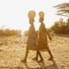 Women walking in Africa with water barrels on their heads 