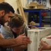 Two students working on a cooler device for long term storage of medical supplies following natural disasters.