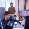 Three graduate students discuss a project in their office space