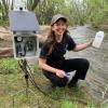 Emily Bedell collecting a sample from a river