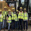Kiewit Design-Build Scholars at a job site with video play button graphic