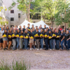 Large group of CU Engineering Kiewit scholars standing in front of engineering building holding a yellow hard hat.