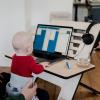 A woman works at her computer with her baby in her lap