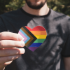 A person holding a heart displaying Pride colors