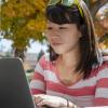 A student works on a computer at an outdoor table. 