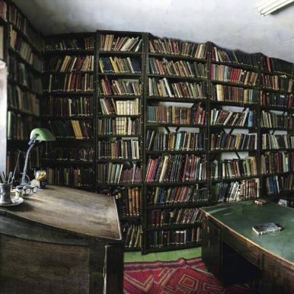 A room with a desk and stacks of books