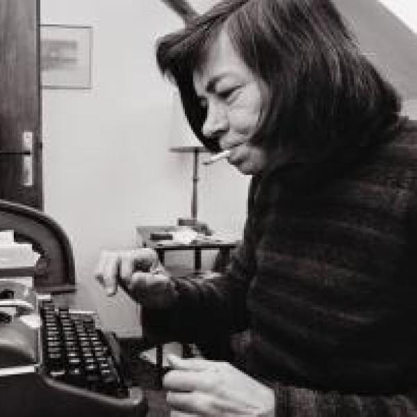 A woman is sitting at a desk in front of a typewriter