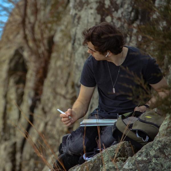 A man writing in a notebook outdoors