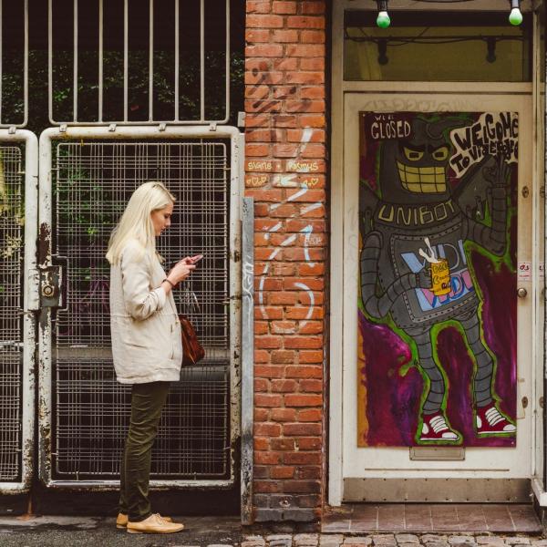 woman standing beside building holding smartphone