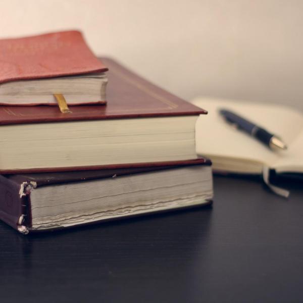 three books and a pen on a planner