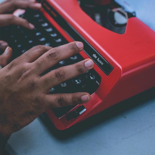 A person typing on a red typewriter