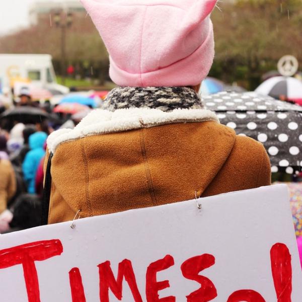 Woman with a pink hat and a sign that reads Times Up