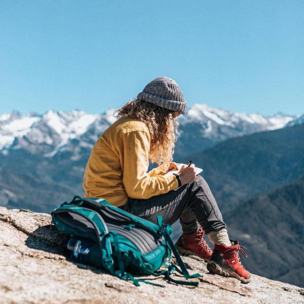 woman writing on top of a mountain