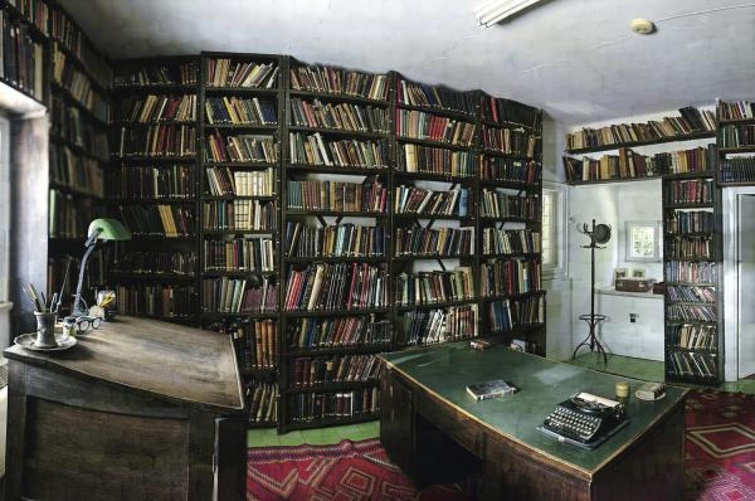 A room with a desk and stacks of books