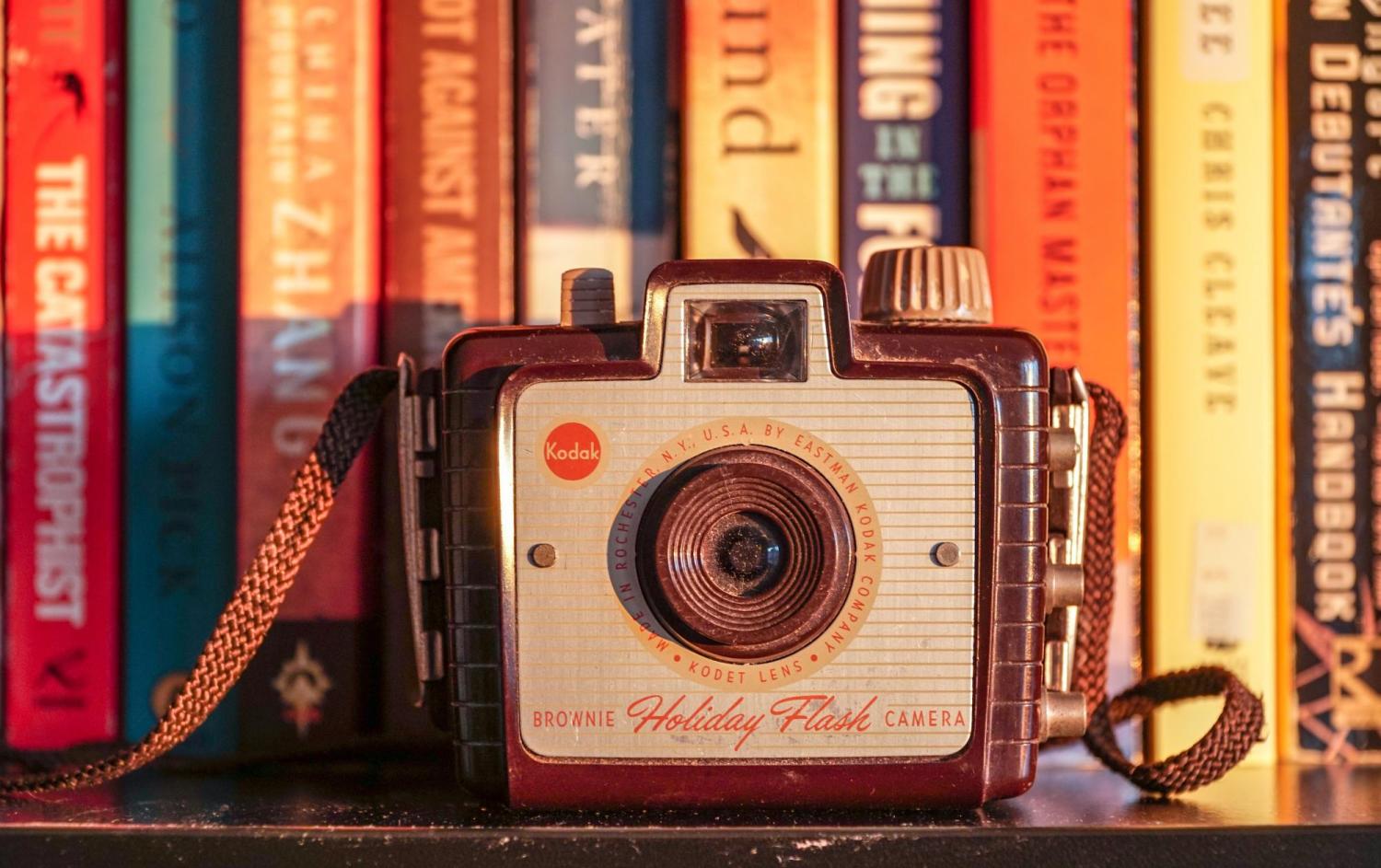 GREY CAMERA AGAINST BOOKS BACKDROP